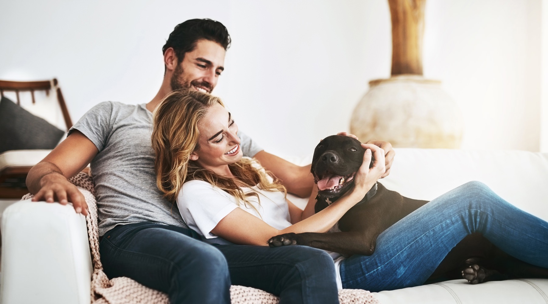 We're a pet friendly community man and woman sitting on couch with a dog