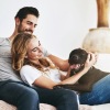 man and woman sitting on couch with a dog